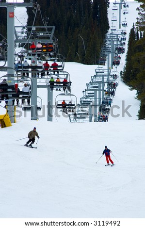 Very busy snow ski resort with four person chair lift