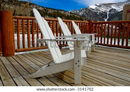 white deck chairs in the mountains on a sunny, blue sky day at a ski resort
