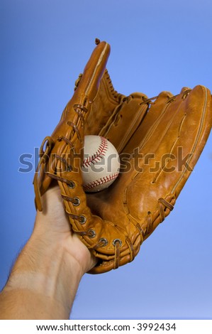 Baseball in leather glove against blue sky