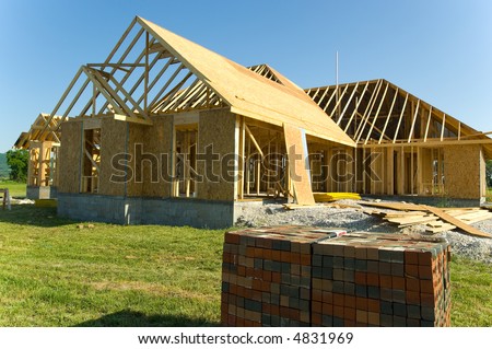 New home under construction with wood, trusses and supplies against blue sky