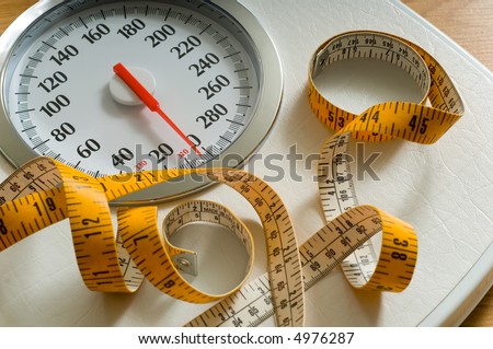 Bathroom scale with large dial and tape measure.  Theme of dieting or living healthy