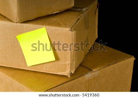 Brown corrugated boxes with a post-it or sticky note to add copy, on a black background