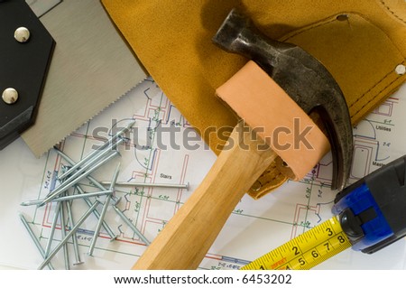 Handyman or construction worker items including a leather tool belt, a hammer, a saw, nails, a measuring tape and a house floor plan