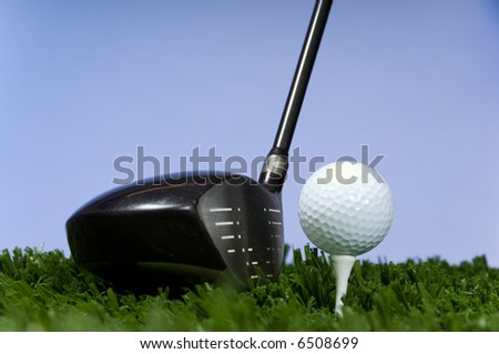 Golf club and ball on a tee in front of a blue sky background , room for copy