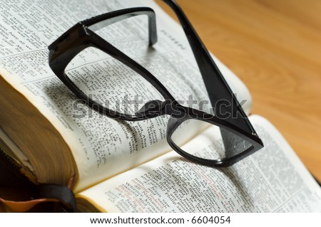 A pair of ladies reading glasses on top of a a Bible, religious study