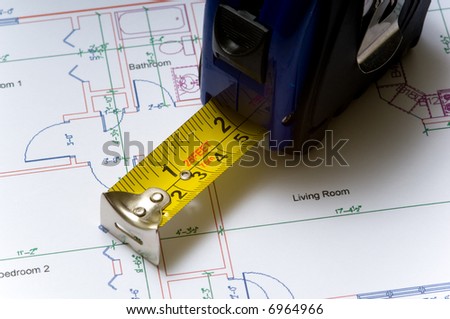 A tape measure slightly open lying on top of a house floor plan, construction industry or real esate