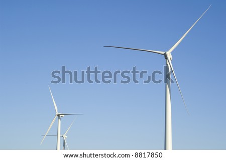 Energy producing wind turbines against a blue sky with copy space