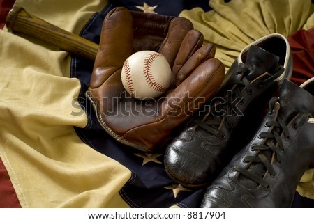 Vintage, antique baseball gear on vintage American flag bunting, inlcuding a baseball mitt or glove, baseball shoes or cleats, a baseball bat and a baseball. sports background