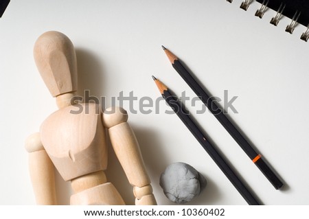 A drawers tools including a wooden people poser, pencils, eraser on a sketch tablet