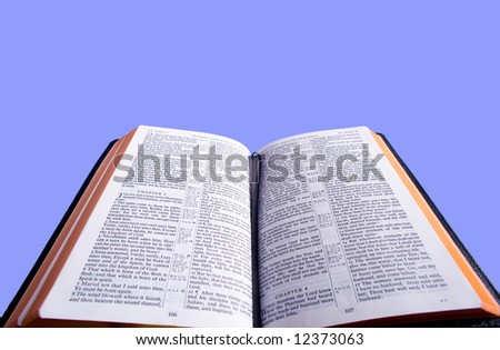 An open Bible in front of a blue sky background with copy space.  Bible version is the King James version of the bible which is in the public domain