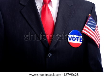 A man wearing a blue business suit and tie with a vote button and US flag.  Election day background or concept