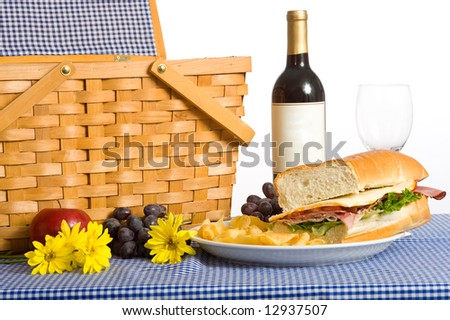 A picnic lunch consisting of a sandwich, potato chips and grapes on a Blue gingham or checked tablecloth