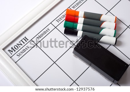 Blank white calendar with dry erase markers and an eraser