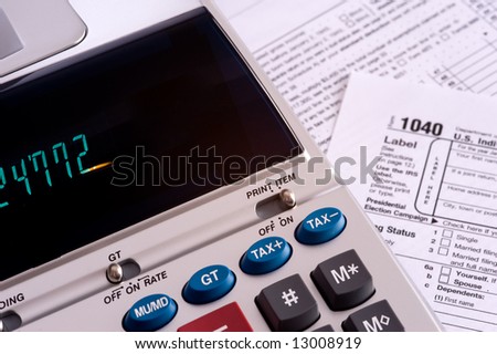 An adding machine or calculator with adding machine tape or paper and tax forms