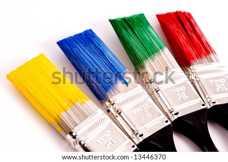 A row of primary colored paint brushes on white background with copy space