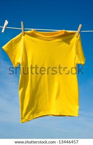 A yellow colored T-shirts hanging on a clothesline on a beautiful, sunny day, add text or graphic to shirts or copy space