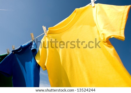 a yellow and blue colored T-shirt hanging on a clothesline on a beautiful, sunny day, add text or graphic to shirts or copy space