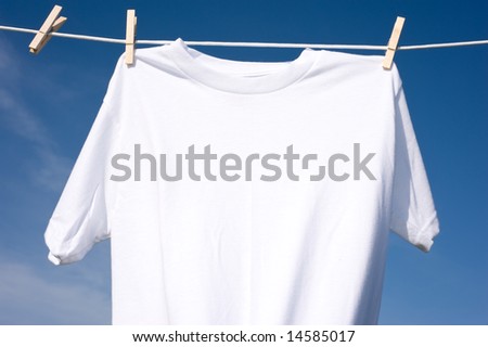 A plain white T-shirt hanging on a clothesline on a beautiful, sunny day, add text or graphic to shirts or copy space