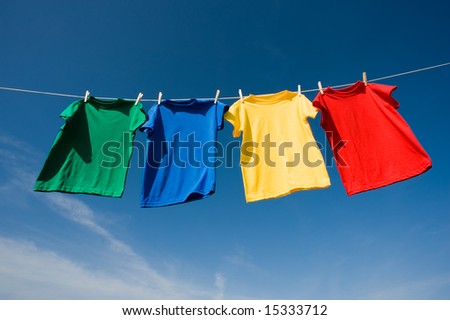 a set of primary colored T-shirts hanging on a clothesline on a beautiful, sunny day, add text or graphic to shirts or copy space