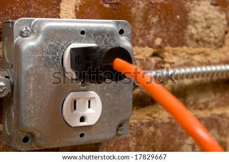 Electrical plug on a brick wall with a cord or extension cord plugged in, concept of connecting or power
