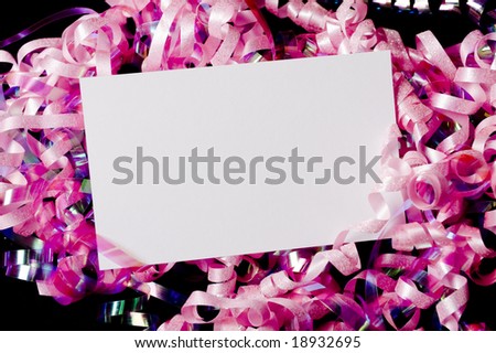 A blank white note card or note surrounded by curly ribbons or bows on black