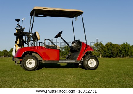 A red golf cart or buggy on a golf course with golf clubs etc