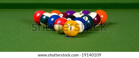 A game of pool with the balls lined up in an 8-ball formation on a green felt pool table
