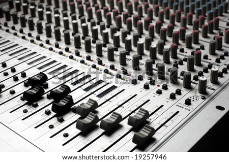 Audio recording equipment or soundboard background with many knobs and adjustments, board is a little dusty