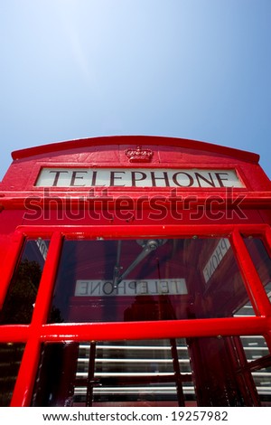 A red telephone booth from England in fron of a blue sky