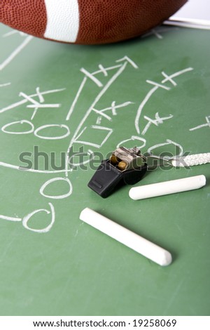 A diagram of a football play on a chalkboard with a football, chalk, eraser ane a whistle