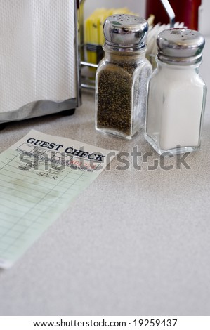 A cafe or restaurant table top background with salt and pepper shakers, napkin holder, guest check etc,