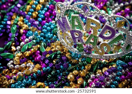 A colorful mardi gras crown or tiara lying on top of beads, holiday theme