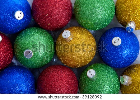 A background comprised of blue, green, red and gold glittery Christmas ornaments