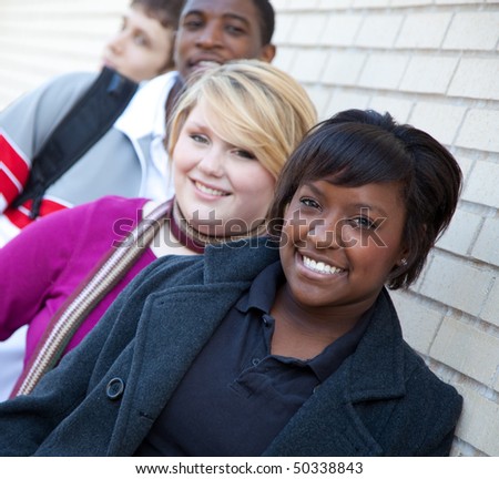 Multi-racial college students, friends outside against a brick wall