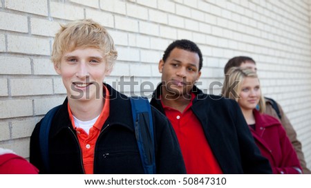 Multi-racial college students/friends outside against a brick wall