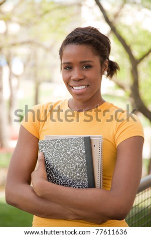 African American Female College Student outdoors with books