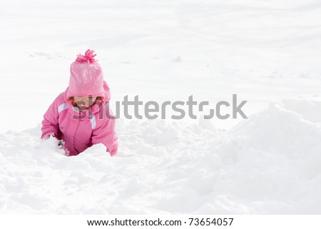 A little girl playing in a snow pile.
