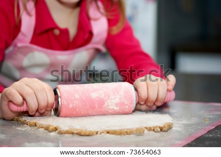 Close-up of child with a rolling pin baking cookies