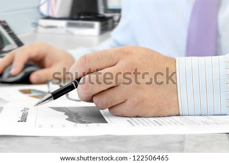 Male Hand with Pen Analyzing  Financial Data  in the Office