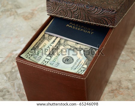 Brown leather box with us dollars and passport on the table