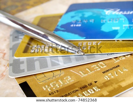 Silver pen on the pile of credit cards .
