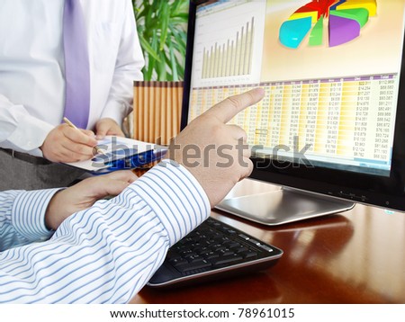 Analyzing  financial data and charts on computer screen.