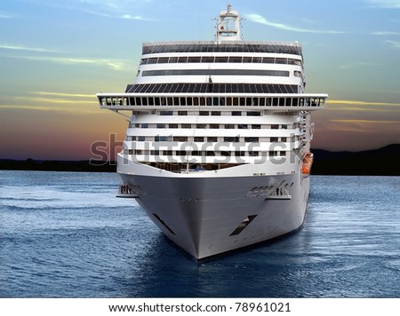 Luxury cruise ship sailing from port on sunset.