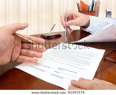 Male hands with pens signing a contract.
