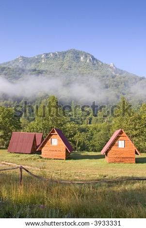 Misty morning in mountain camp. Small wooden houses in camp.