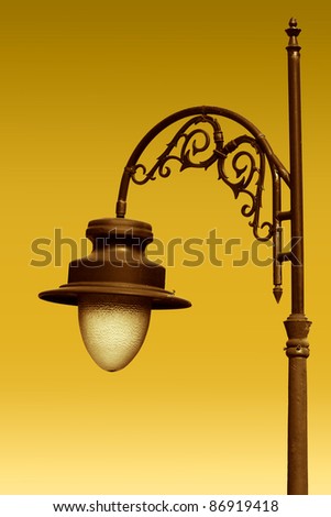 Aged gilded street lamp over yellow background