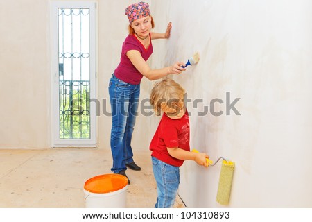 Little boy making renovation with mother, painting the wall