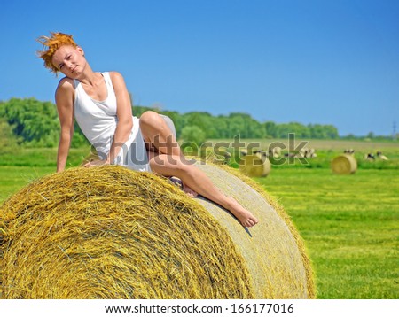 Young woman having fun on the field with big hay bale rolls