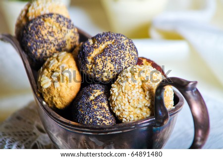 Close up of round shaped cookies decorated with pop seeds in old fashioned sauce-boat