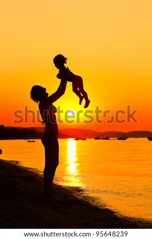 Silhouette of mother and child in a sunset near the water